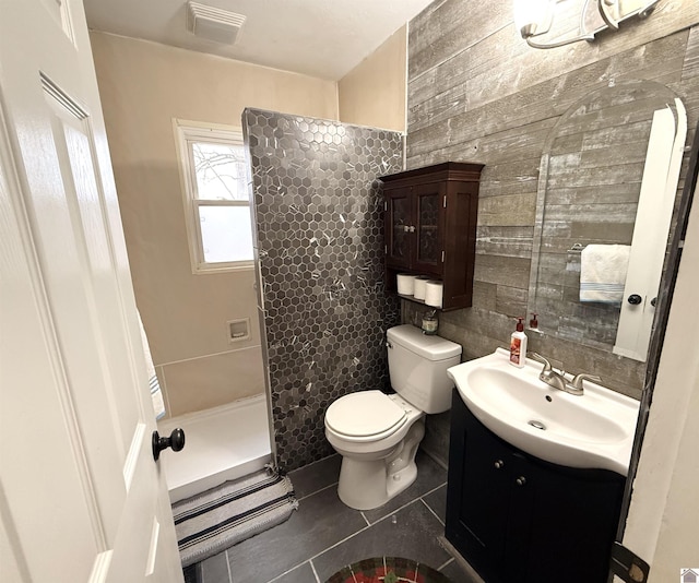 bathroom featuring tile patterned flooring, vanity, toilet, and walk in shower