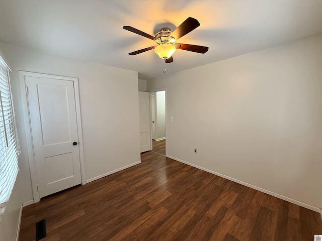 unfurnished bedroom with multiple windows, ceiling fan, and dark hardwood / wood-style floors