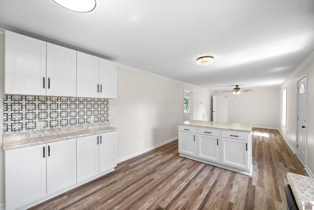 kitchen with light stone countertops, light wood-type flooring, backsplash, ceiling fan, and white cabinets