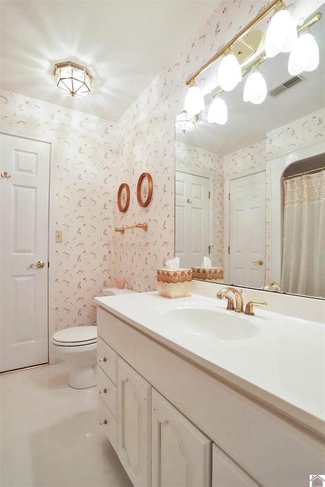 bathroom featuring toilet, vanity, and walk in shower