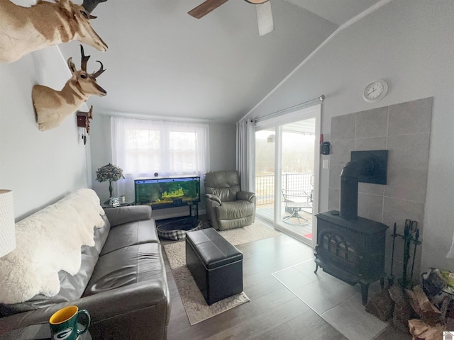 living room featuring vaulted ceiling, a wood stove, and ceiling fan