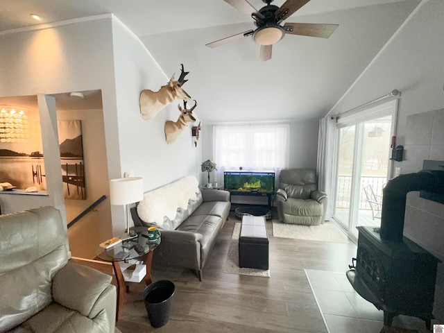 living room with ornamental molding, ceiling fan, hardwood / wood-style flooring, a wood stove, and lofted ceiling