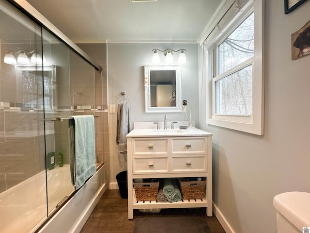 full bathroom featuring hardwood / wood-style floors, vanity, toilet, and bath / shower combo with glass door