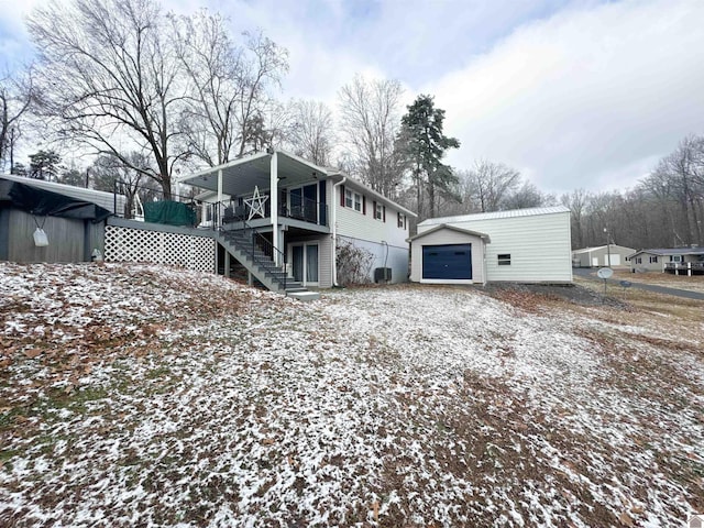 snow covered property with a garage, an outdoor structure, and a wooden deck