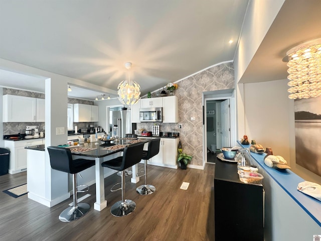 kitchen featuring white cabinetry, dark wood-type flooring, stainless steel appliances, tasteful backsplash, and a notable chandelier