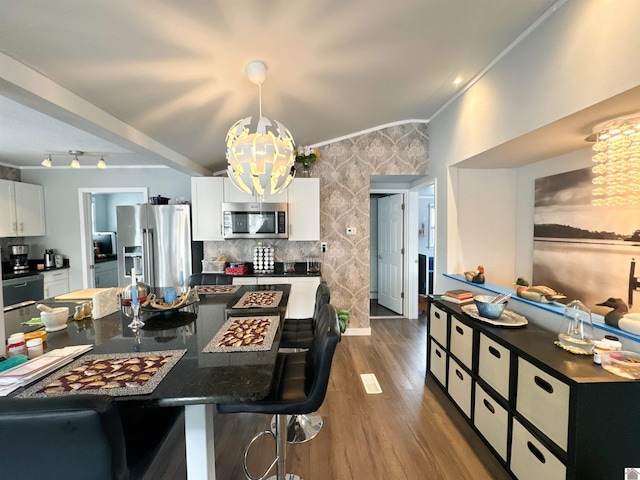 kitchen with pendant lighting, a breakfast bar, dark wood-type flooring, white cabinetry, and stainless steel appliances