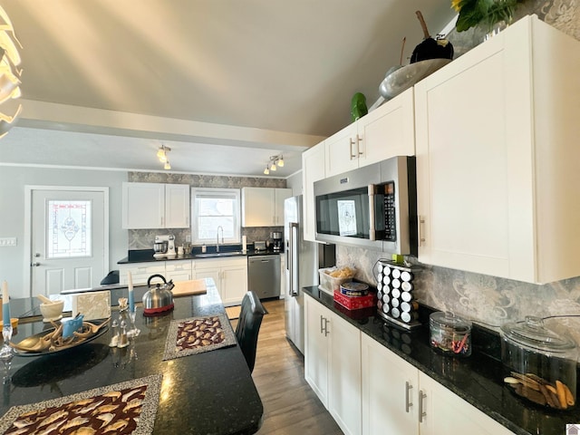 kitchen featuring dark stone countertops, decorative backsplash, white cabinets, and stainless steel appliances