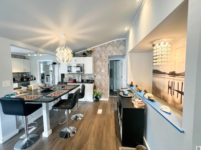 interior space featuring white cabinets, dark wood-type flooring, appliances with stainless steel finishes, and an inviting chandelier