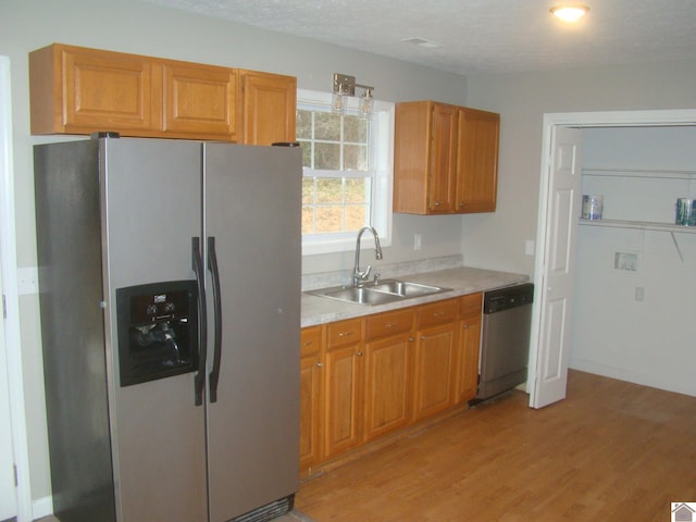 kitchen with sink, light hardwood / wood-style flooring, a textured ceiling, and appliances with stainless steel finishes