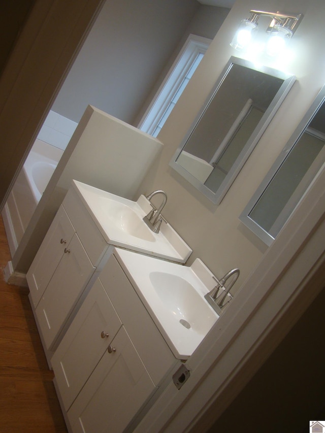 bathroom with hardwood / wood-style flooring, vanity, and a bathtub