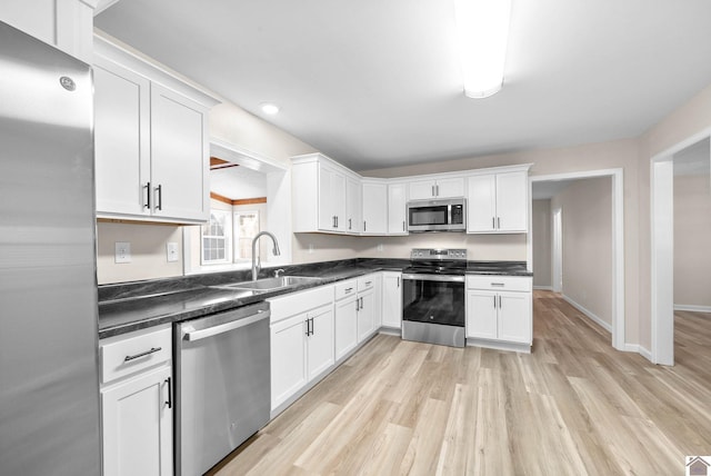 kitchen featuring white cabinetry, sink, light hardwood / wood-style flooring, and appliances with stainless steel finishes