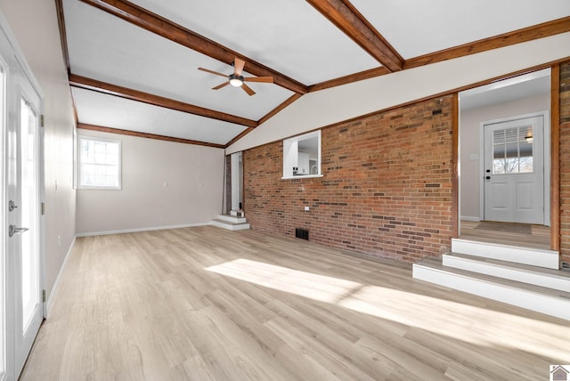 unfurnished living room with ceiling fan, brick wall, a wealth of natural light, and light hardwood / wood-style flooring