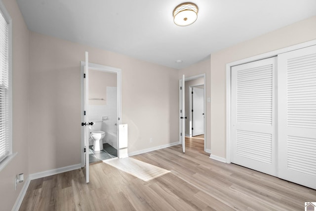 unfurnished bedroom featuring connected bathroom, a closet, and light hardwood / wood-style flooring