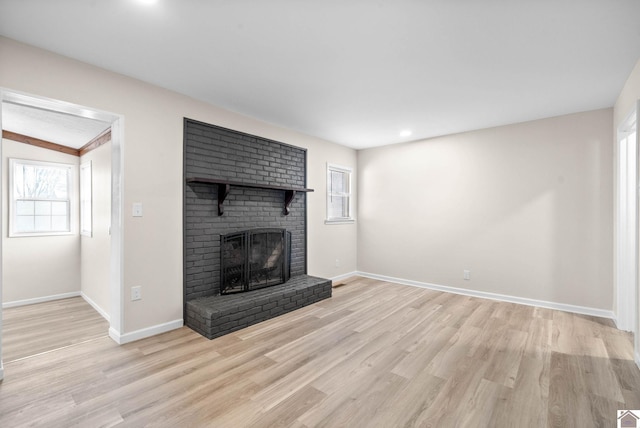 unfurnished living room with light wood-type flooring, lofted ceiling, and a fireplace