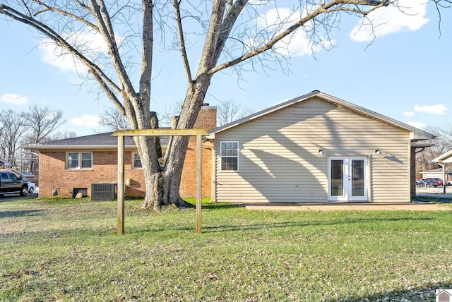 rear view of house featuring a yard, central air condition unit, and french doors