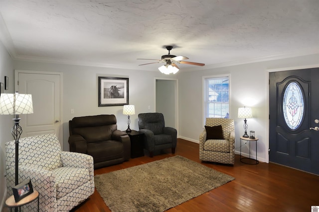 living room with a textured ceiling, dark hardwood / wood-style floors, ceiling fan, and ornamental molding