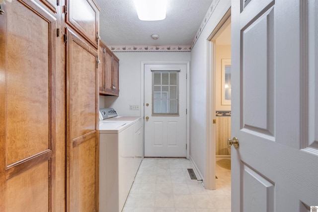 laundry room featuring cabinets, a textured ceiling, and washing machine and clothes dryer