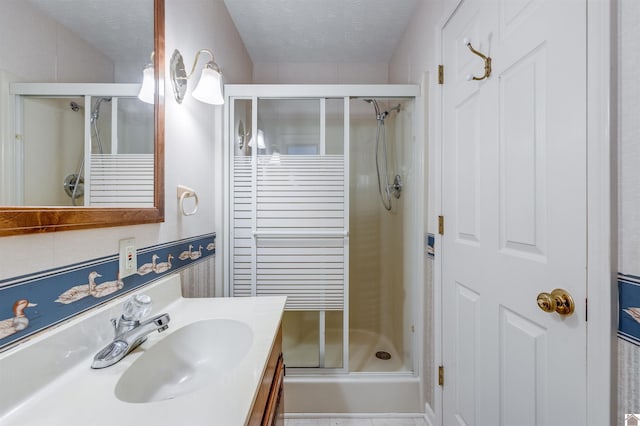 bathroom with vanity, a textured ceiling, and walk in shower