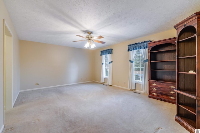 unfurnished living room with light carpet, ceiling fan, and a textured ceiling