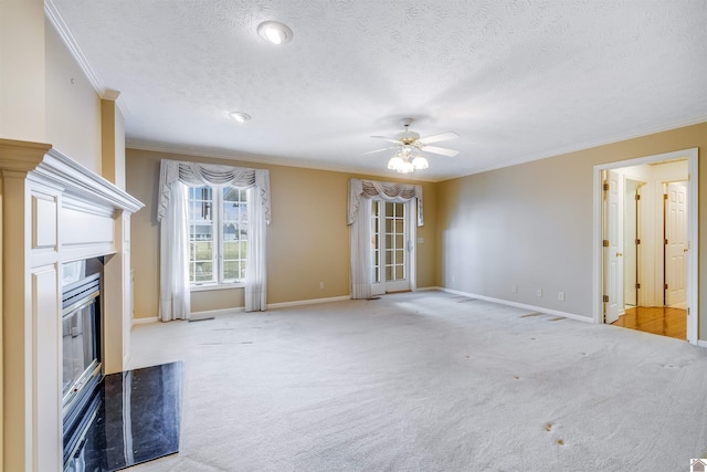 unfurnished living room with ceiling fan, a high end fireplace, light colored carpet, a textured ceiling, and ornamental molding