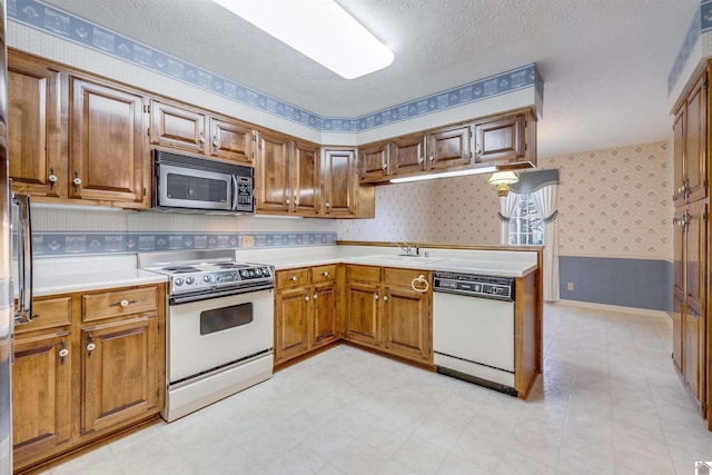 kitchen featuring a textured ceiling, white appliances, and sink