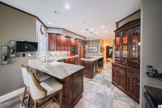 kitchen with sink, backsplash, kitchen peninsula, decorative light fixtures, and a kitchen bar