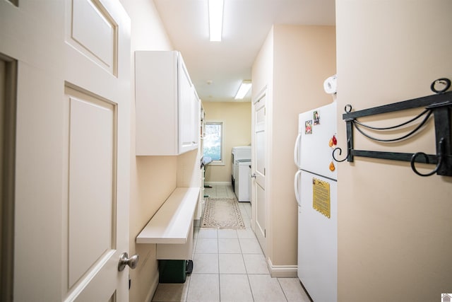 kitchen with white cabinets, washer / dryer, white fridge, and light tile patterned flooring