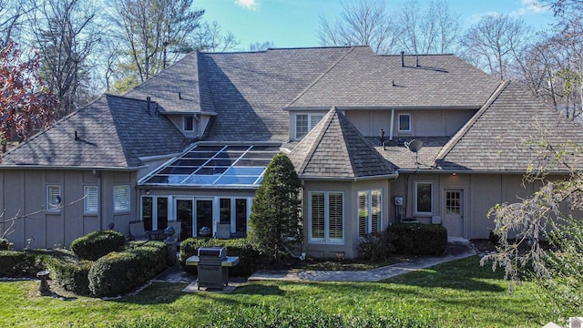 rear view of house featuring solar panels and a yard