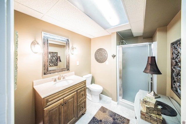 bathroom with a paneled ceiling, vanity, toilet, and a shower with shower door