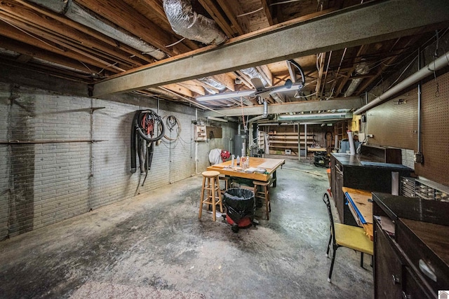 basement featuring a workshop area, gas water heater, and brick wall