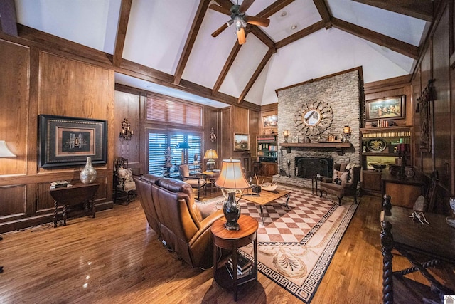 living room with hardwood / wood-style flooring, wood walls, a fireplace, and high vaulted ceiling