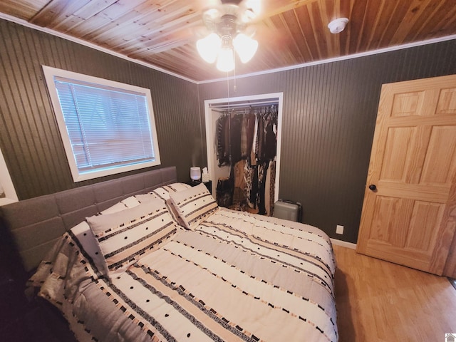 bedroom featuring ceiling fan, crown molding, light hardwood / wood-style flooring, wooden ceiling, and a closet