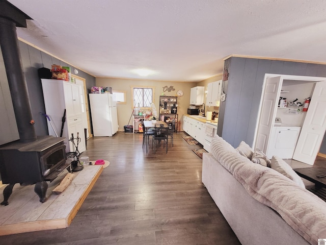 living room with washer / dryer, dark hardwood / wood-style floors, and a wood stove