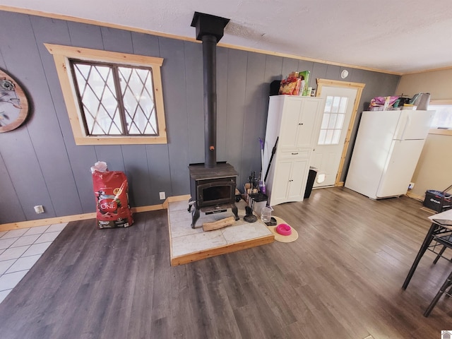 interior space with dark hardwood / wood-style flooring, a wood stove, crown molding, and wooden walls