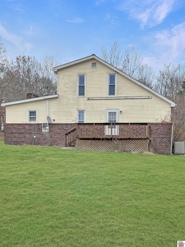 back of property featuring a wooden deck and a yard