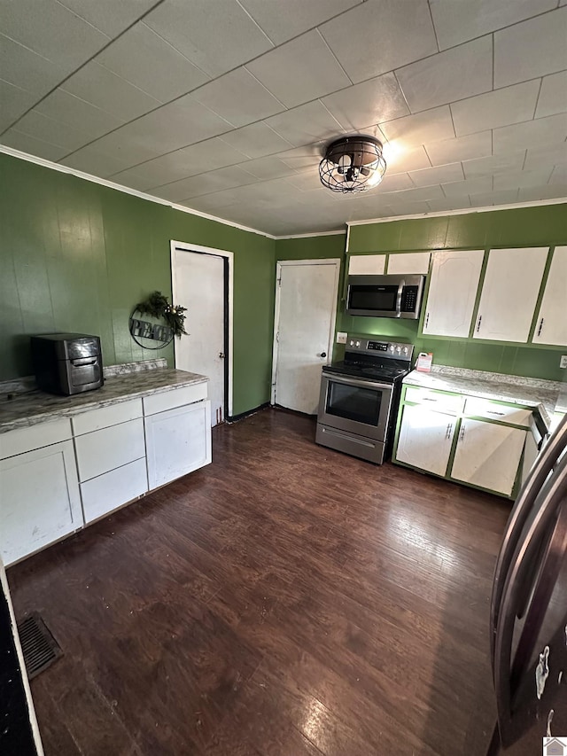 kitchen with white cabinets, dark hardwood / wood-style flooring, stainless steel appliances, and ornamental molding