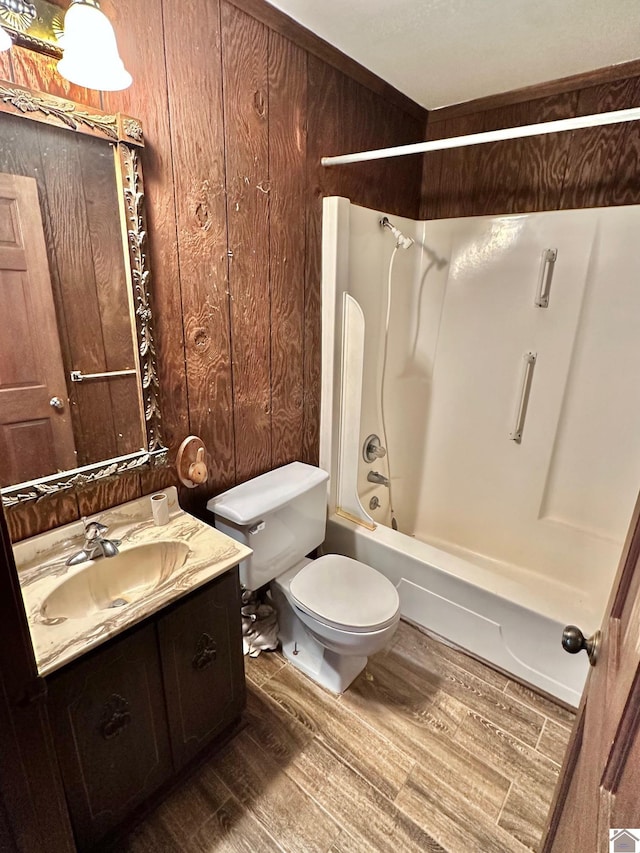 full bathroom featuring shower / bathing tub combination, vanity, wood walls, hardwood / wood-style flooring, and toilet