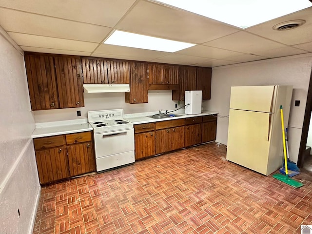 kitchen featuring a drop ceiling, white appliances, and sink