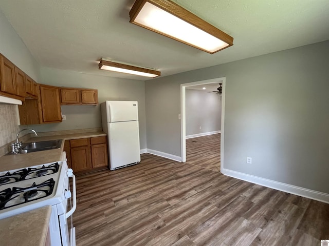 kitchen featuring dark hardwood / wood-style flooring, ceiling fan, sink, and white appliances