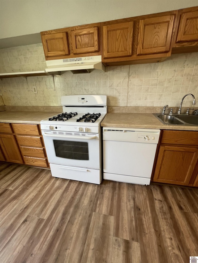 kitchen with hardwood / wood-style floors, backsplash, white appliances, and sink