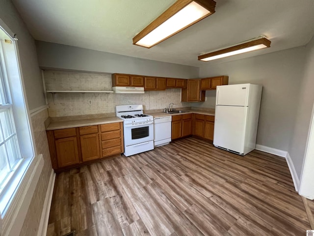 kitchen with decorative backsplash, light wood-type flooring, white appliances, and sink