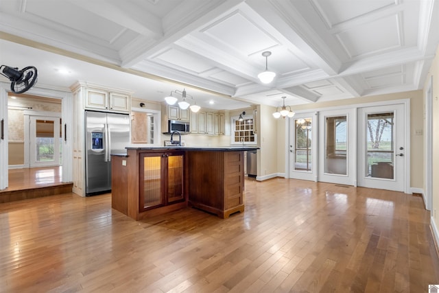 kitchen featuring pendant lighting, a kitchen island with sink, coffered ceiling, cream cabinetry, and stainless steel appliances