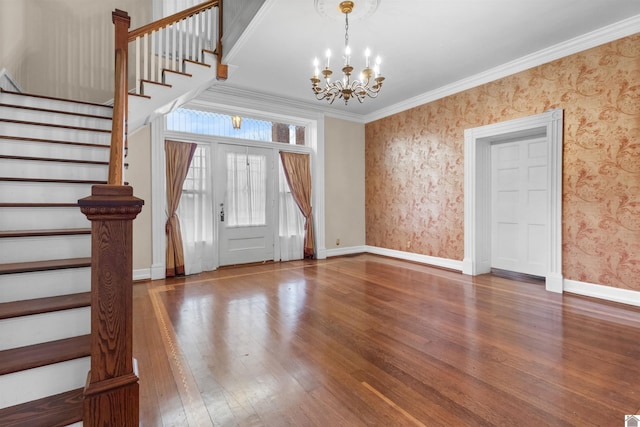 foyer with hardwood / wood-style flooring, crown molding, and an inviting chandelier