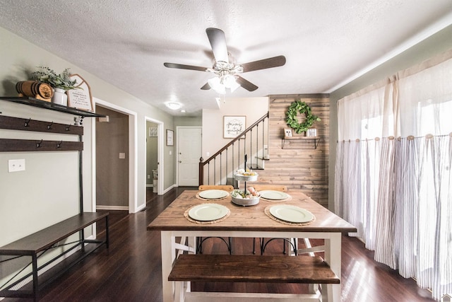 dining space with a textured ceiling, dark wood-type flooring, and wood walls