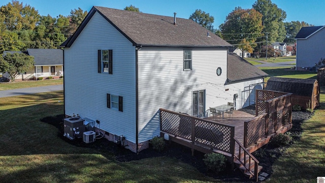 rear view of house featuring central AC, a deck, and a lawn