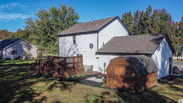 rear view of property featuring a yard, a shed, and a deck