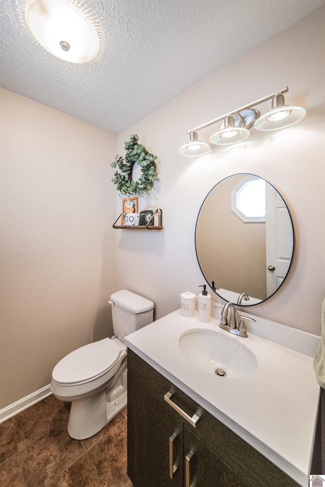 bathroom featuring a textured ceiling, vanity, and toilet