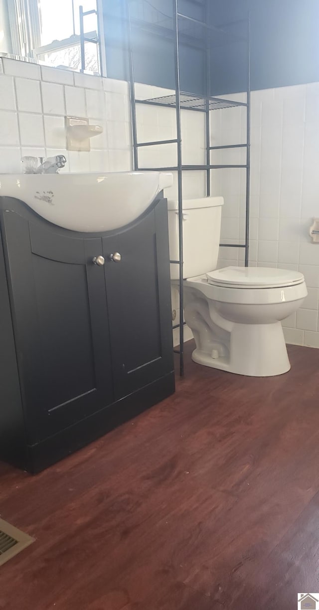 bathroom featuring tile walls, toilet, vanity, and hardwood / wood-style floors