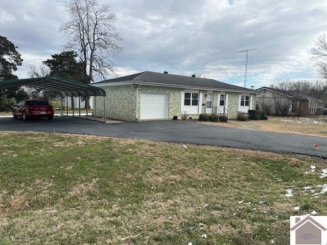 view of front of property featuring a carport, a garage, and a front lawn