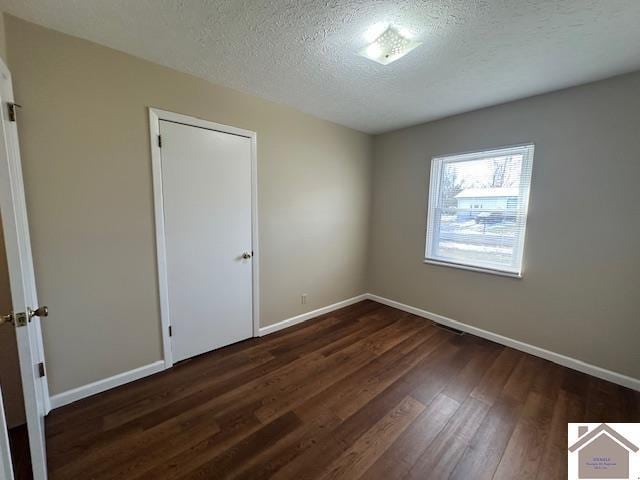 spare room featuring a textured ceiling and dark hardwood / wood-style floors